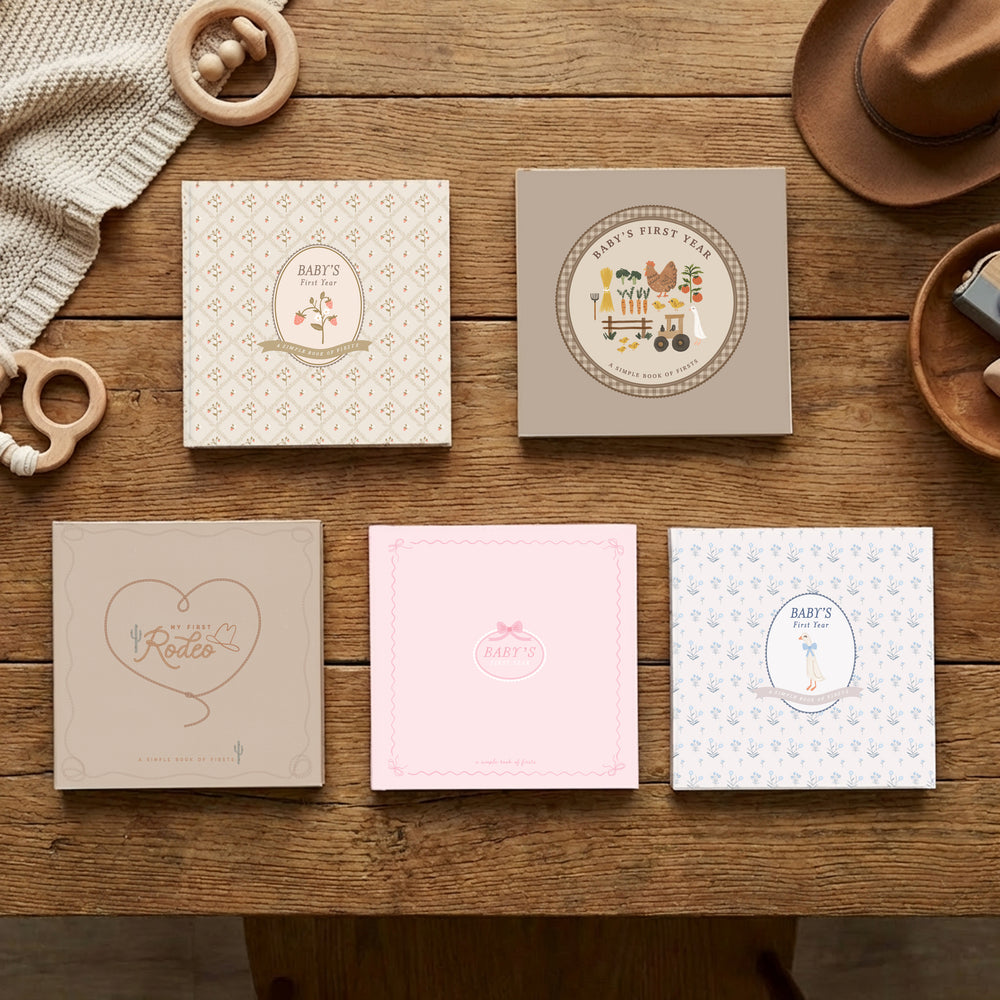 Five illustrated Lucy Darling baby memory books laid side by side