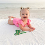 11-month beach milestone photo with Little Artist pennant