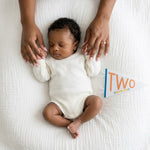 2-month milestone photo with mom's hands and Little Kaleidoscope pennant